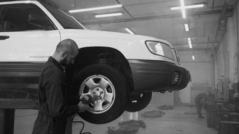 Mechanic using an impact wrench on a car wheel